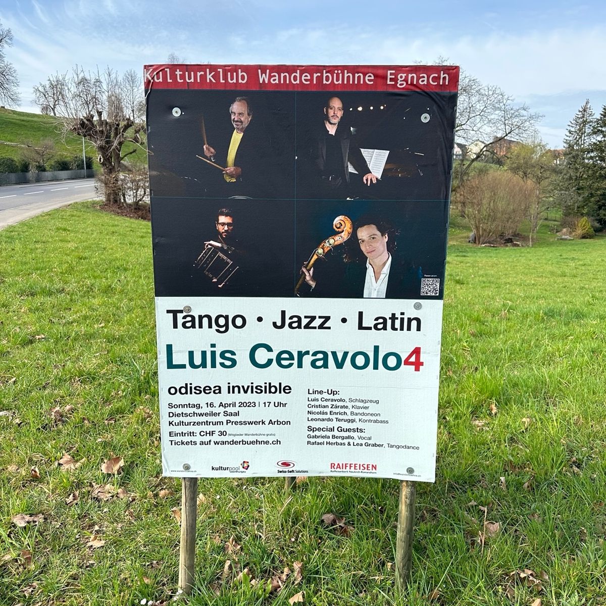 A poster for Luis Ceravolo 4, «Odisea Invisible», standing in a field by the road in Arbon, Switzerland, April 2023